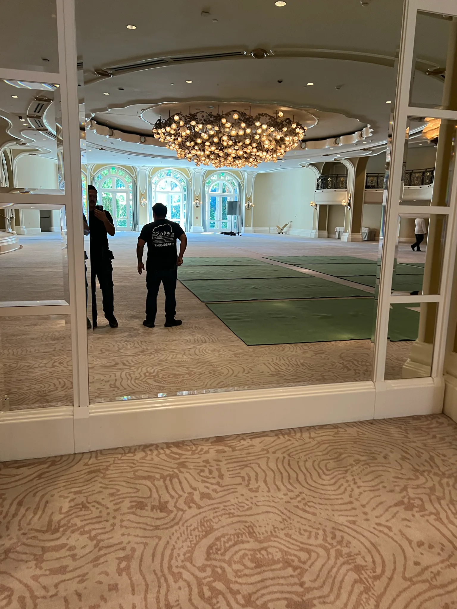Work in progress: green carpet panels laid across the ballroom beneath chandeliers at The Beverly Hills Hotel