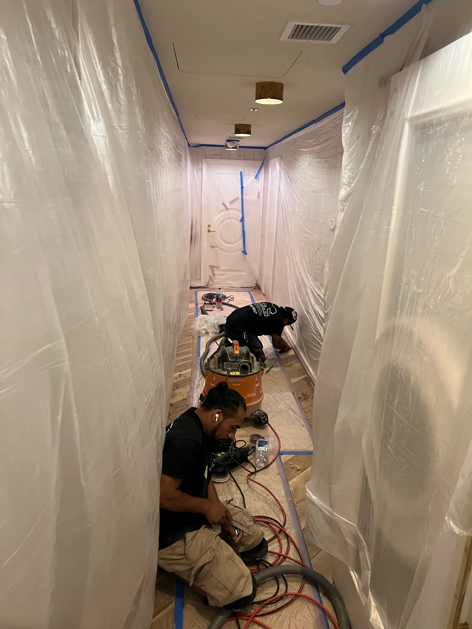 Work in progress: crew sanding a corridor floor under plastic containment at The Beverly Hills Hotel