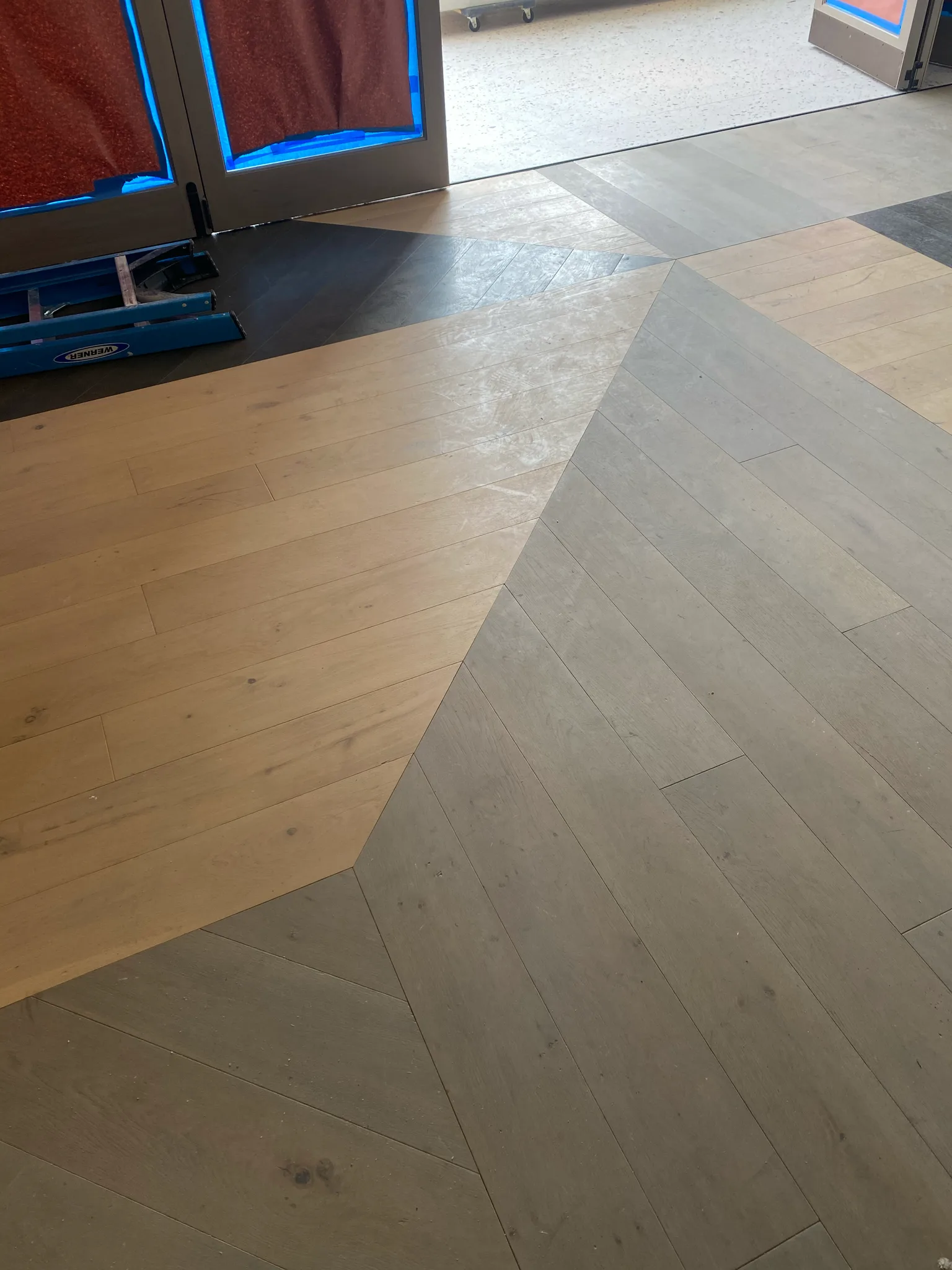 Light and gray wood planks meeting in a geometric pattern at the Esperanza entrance — flooring by Cal Coast Flooring