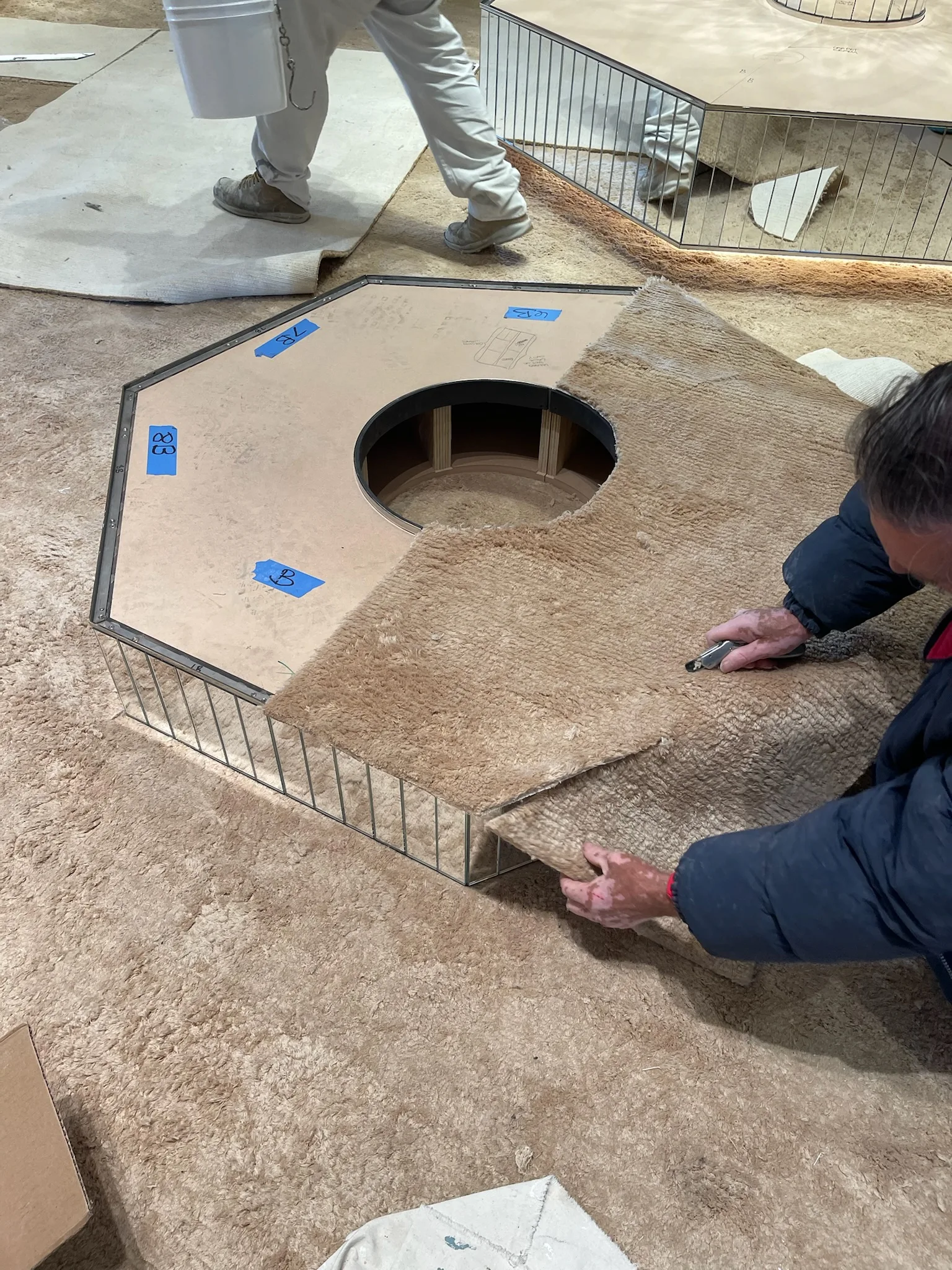 Cal Coast Flooring crew cutting plush carpet around a mirrored plinth at Gucci Melrose Place