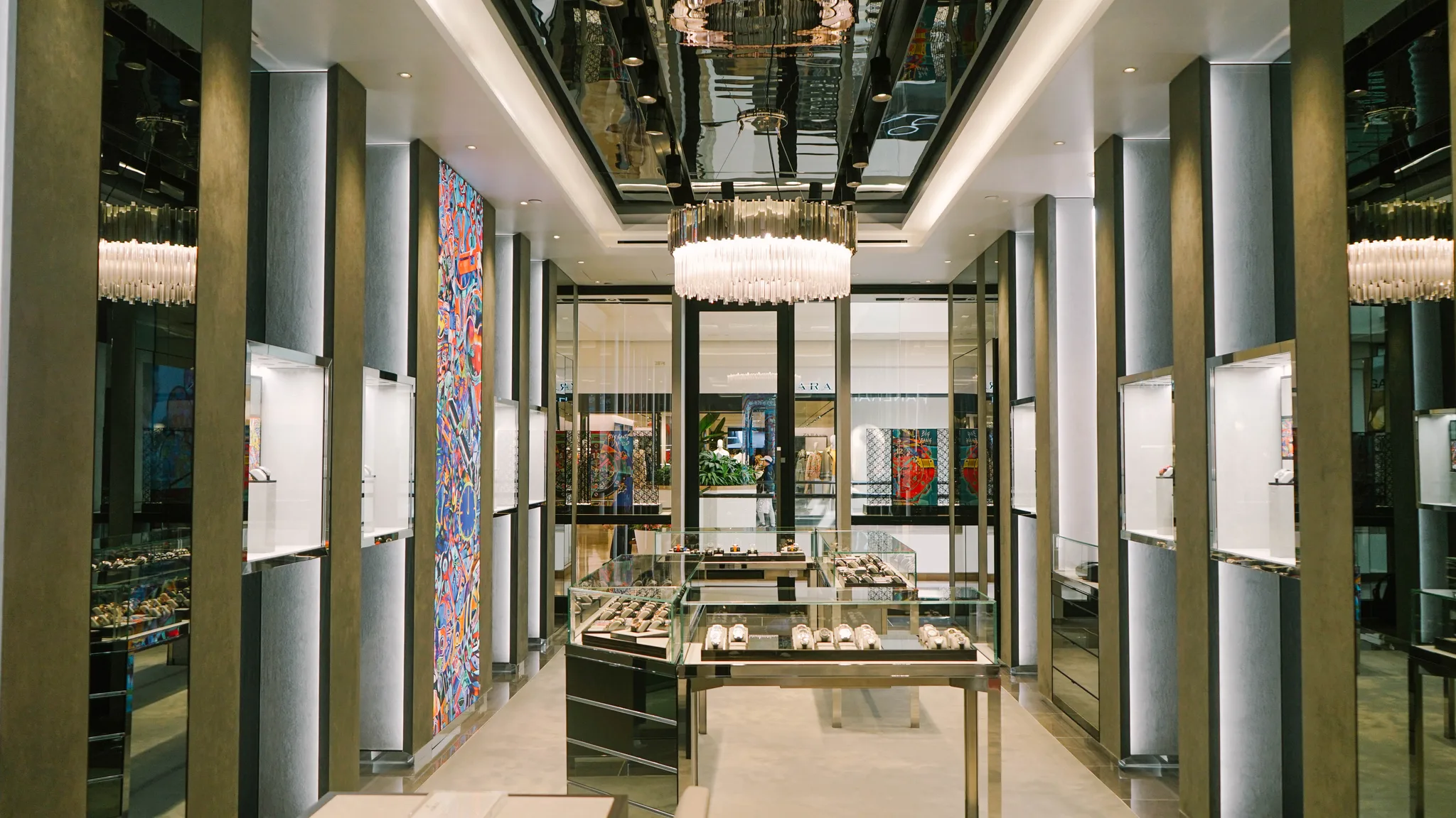 Plush grey carpet through a Hublot boutique, between mirrored display walls and watch cases under a chandelier
