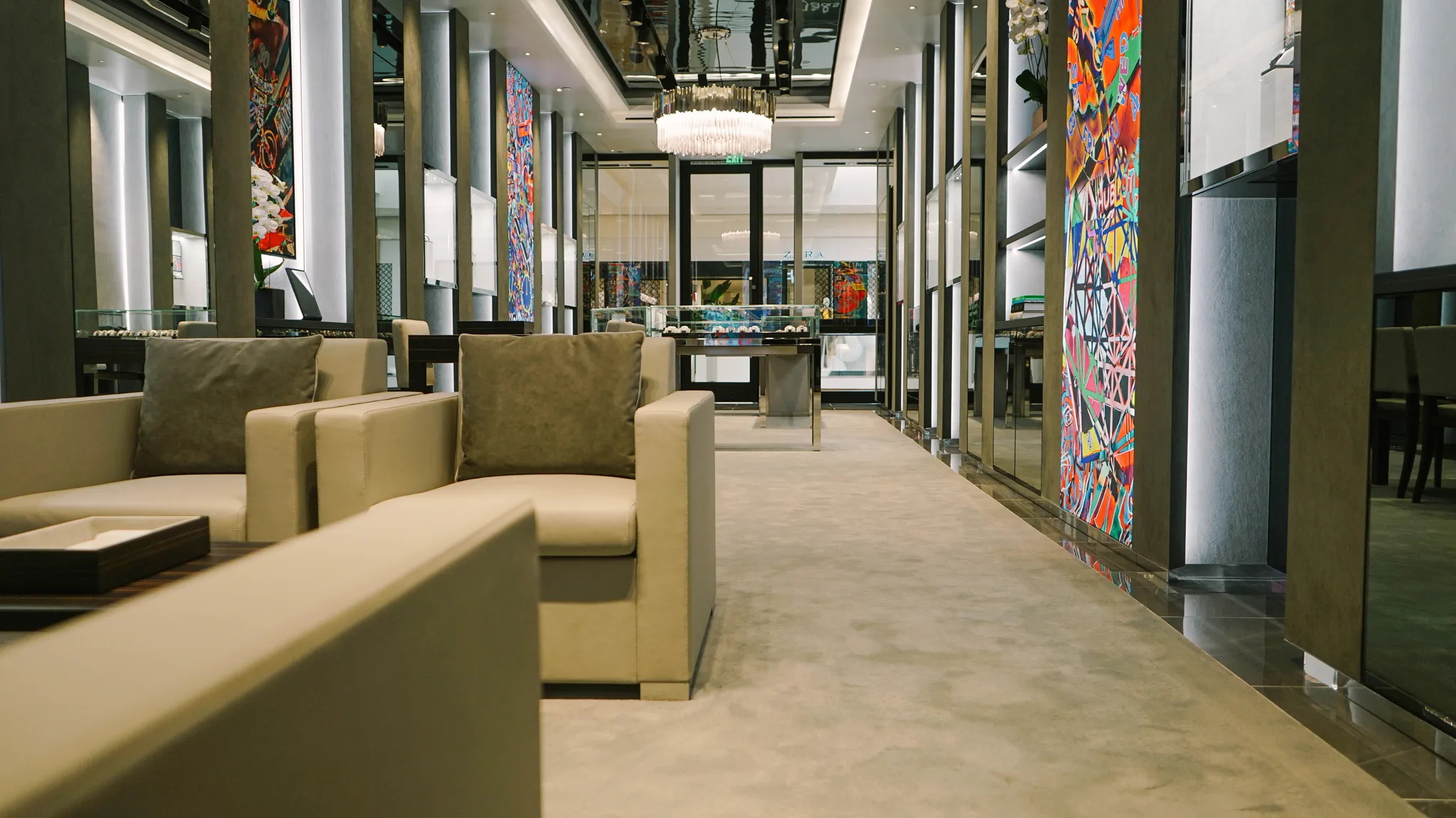 Grey carpet across the lounge seating area of a Hublot boutique, polished stone border along the mirrored wall