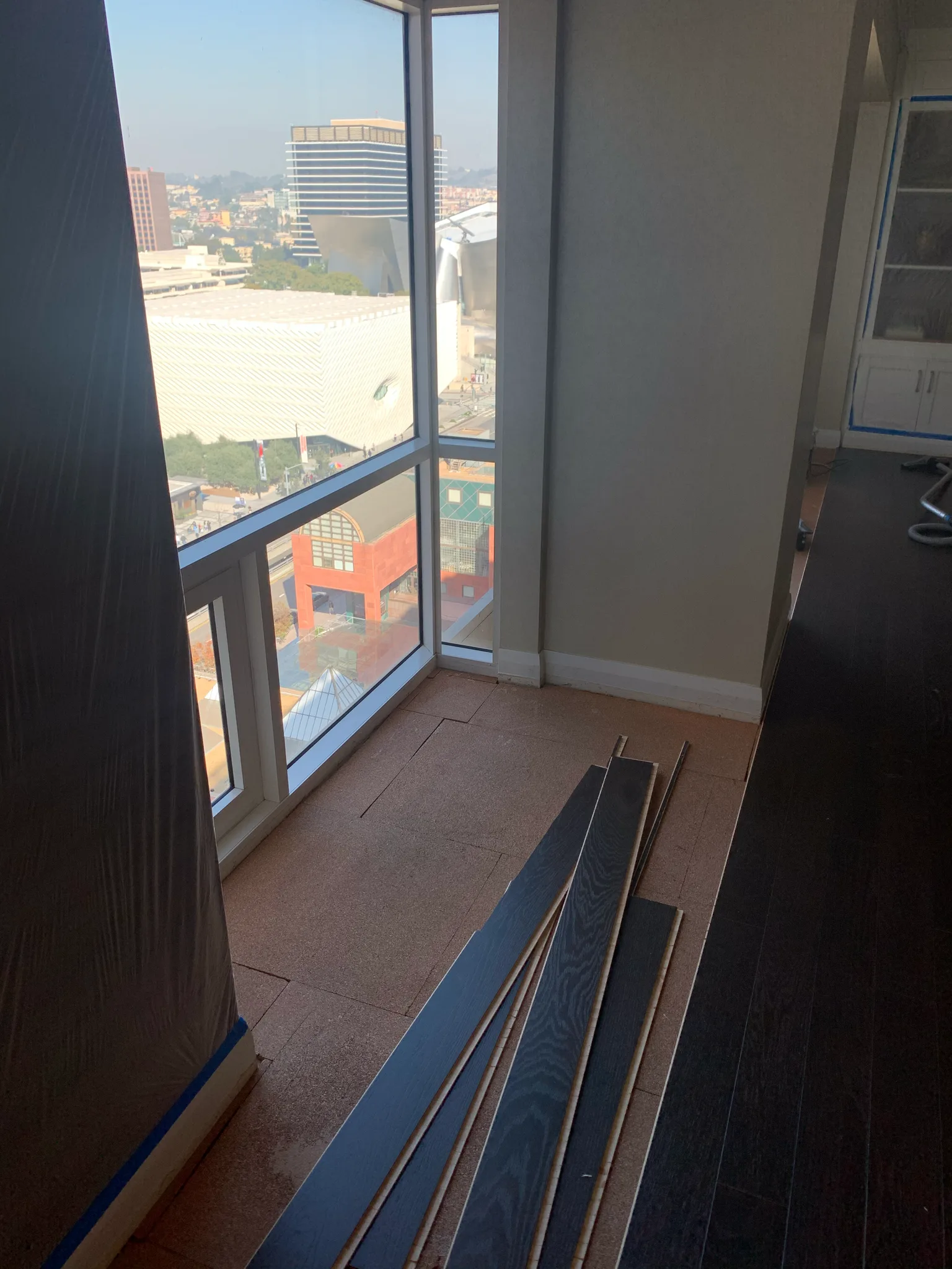 Cal Coast Flooring's dark hardwood planks staged over cork underlay by a downtown-view window at Omni Los Angeles
