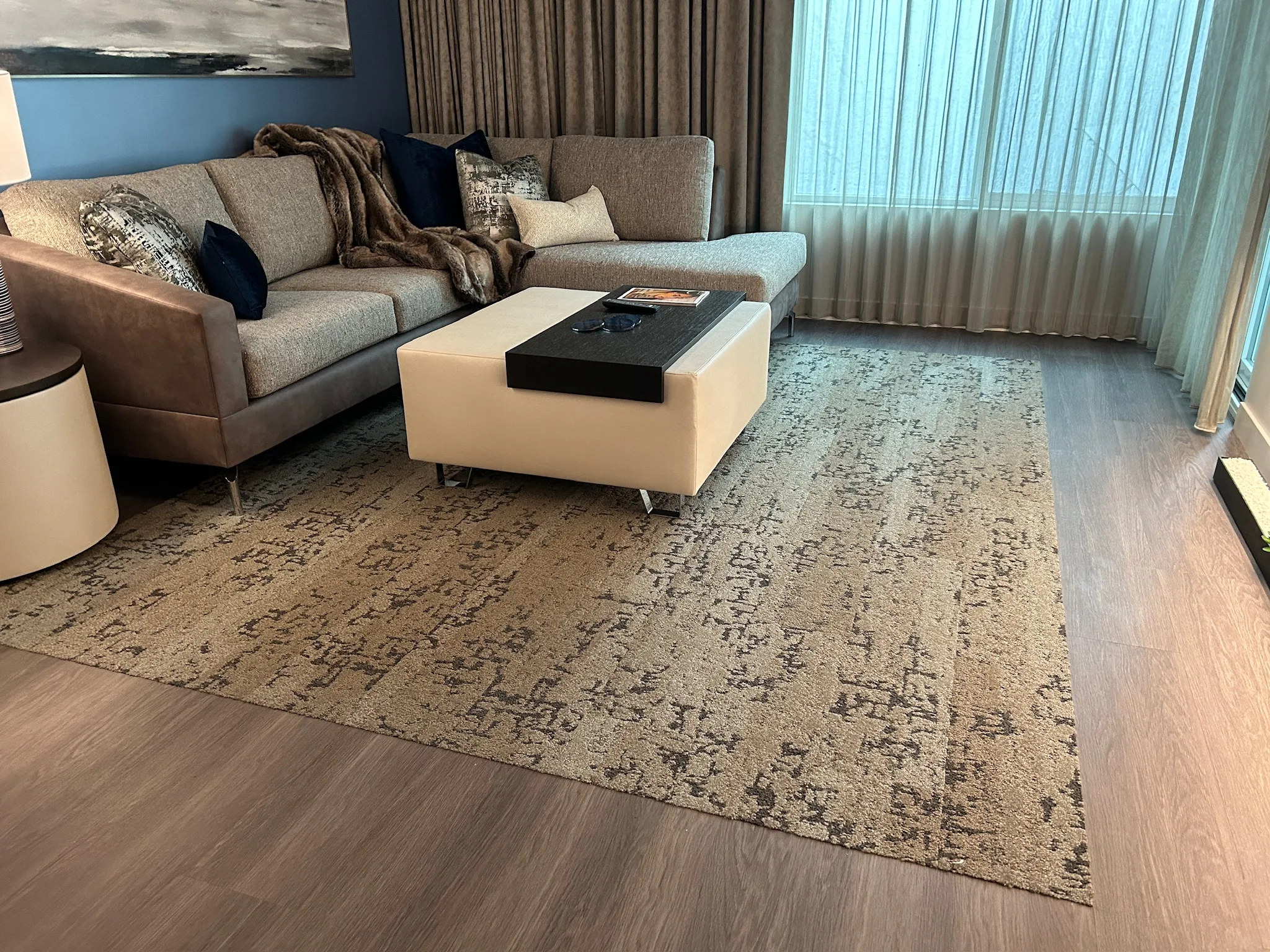 Gray wood-look plank floor beneath the area rug and sectional in a Sunset Marquis suite