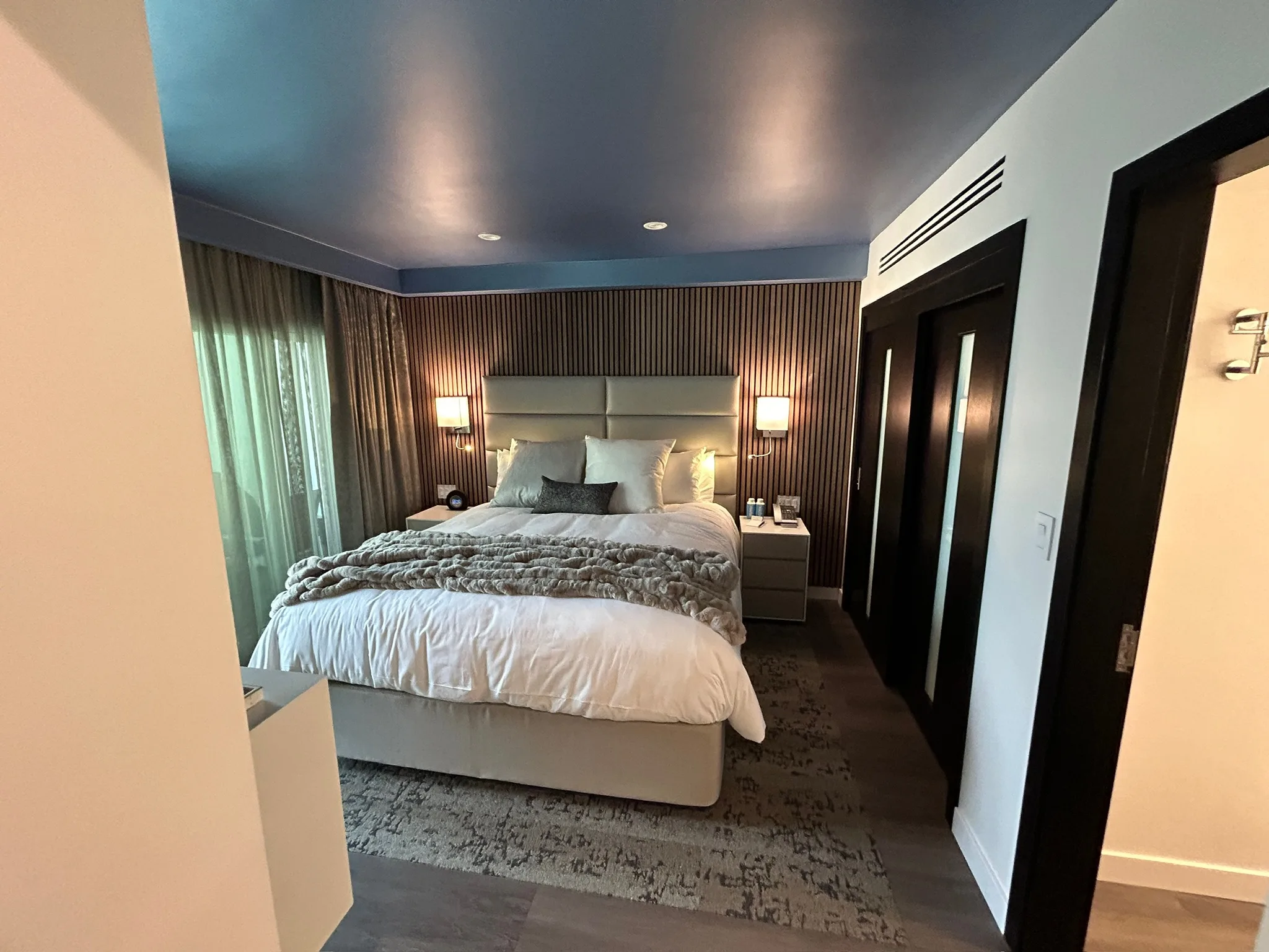 Plank flooring in a Sunset Marquis guest bedroom beside the slatted wood feature wall