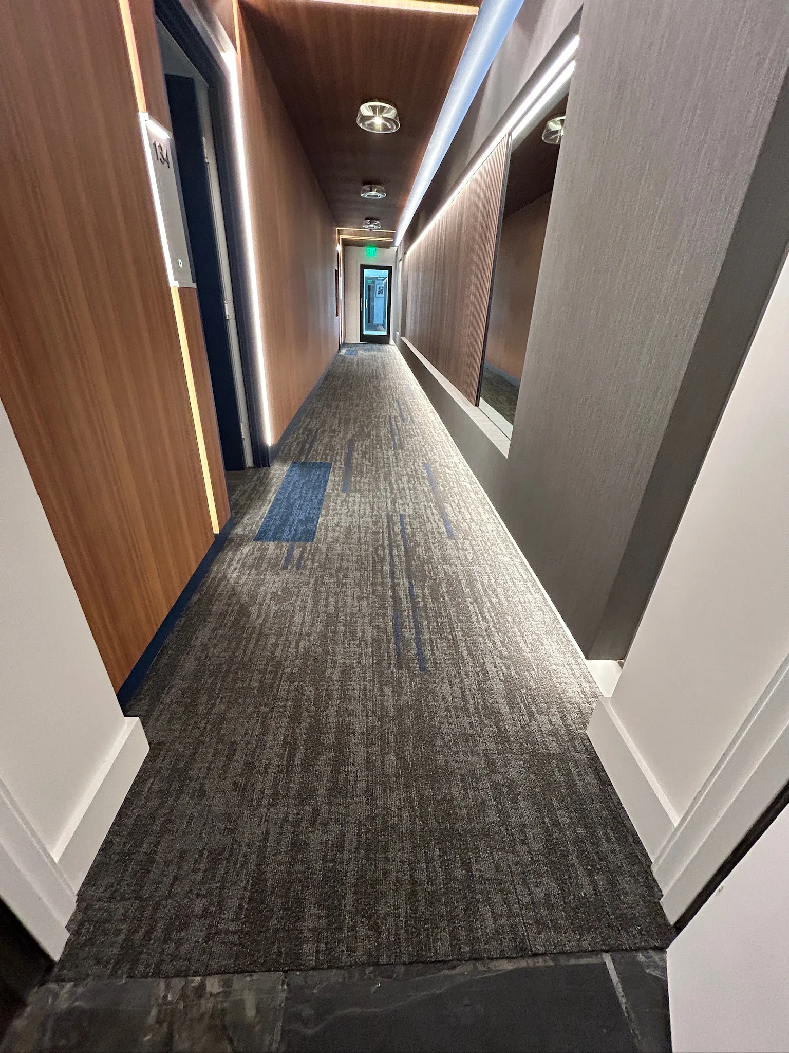 Corridor carpet tile meeting the stone threshold at a Sunset Marquis guest-room door