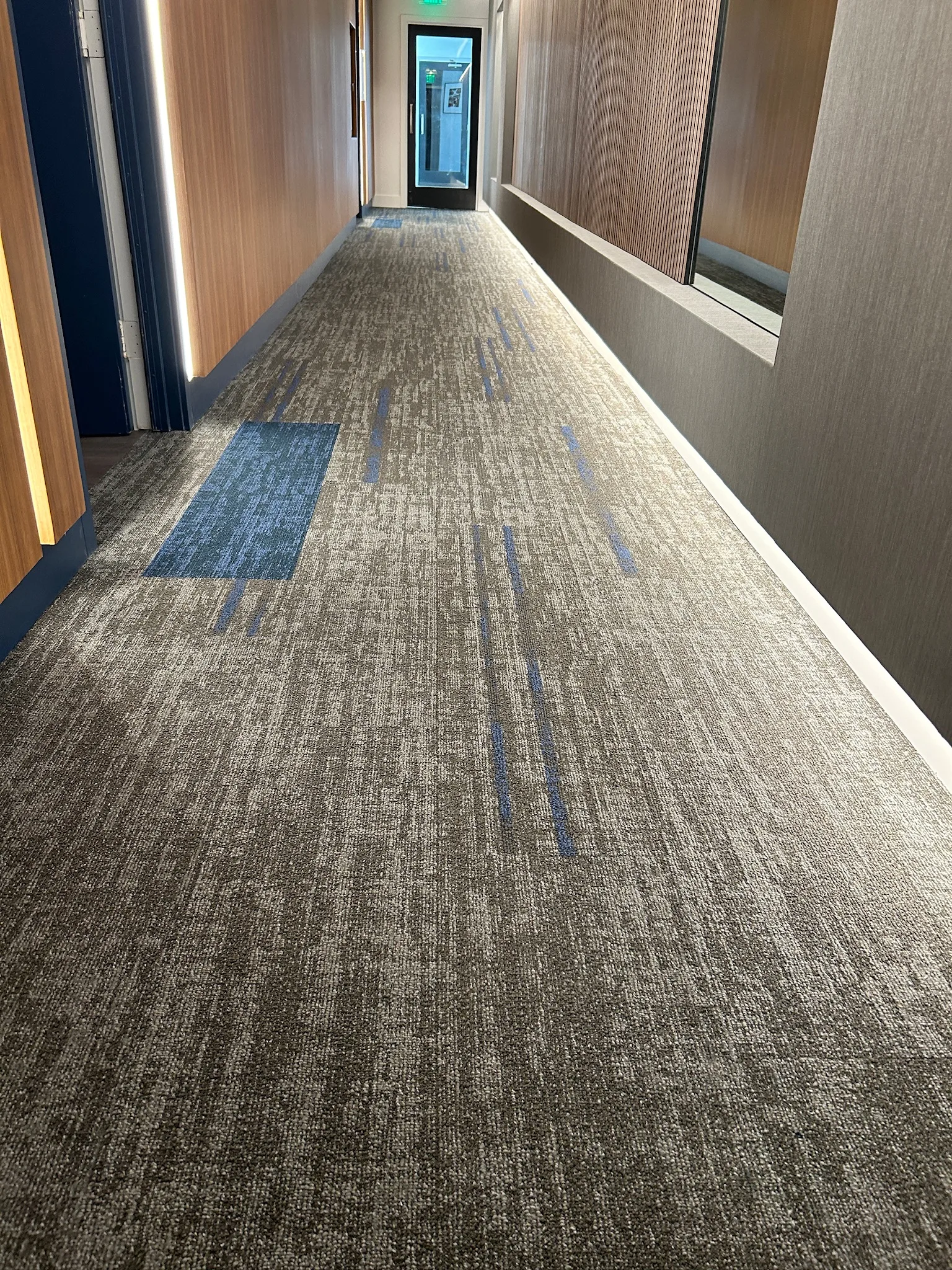 Gray carpet tile with blue accent tiles along a Sunset Marquis corridor, installed by Cal Coast Flooring