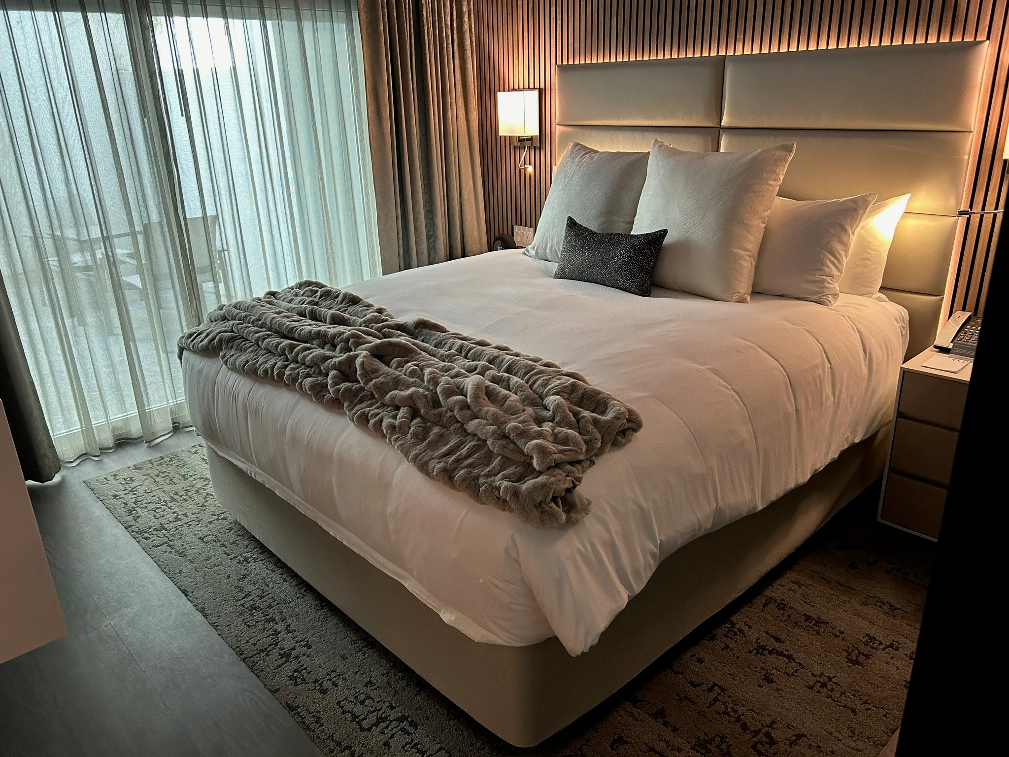 Guest bed dressed at the Sunset Marquis, plank floor and rug beneath