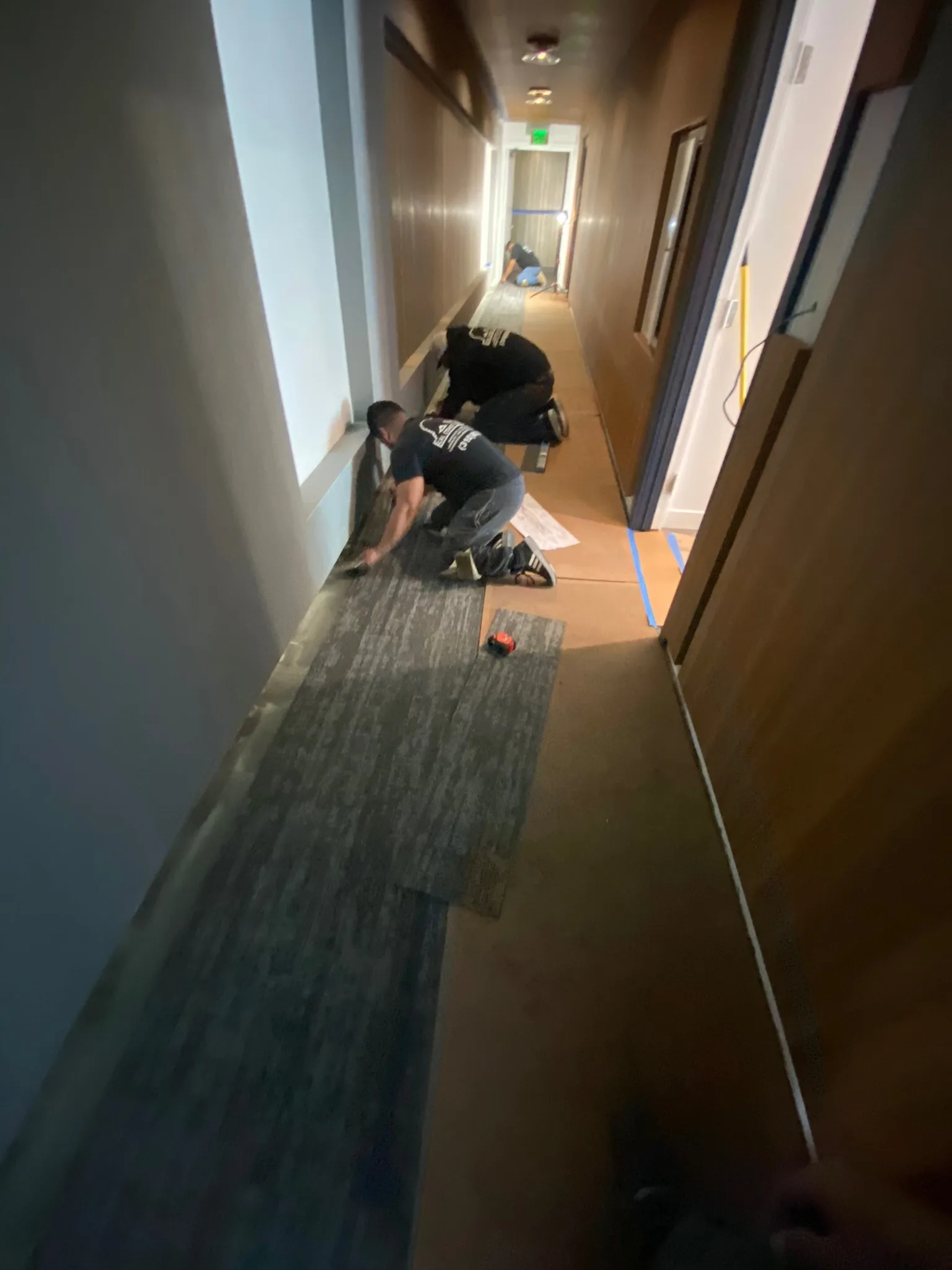 Cal Coast Flooring crew laying carpet tile along a Sunset Marquis guest corridor