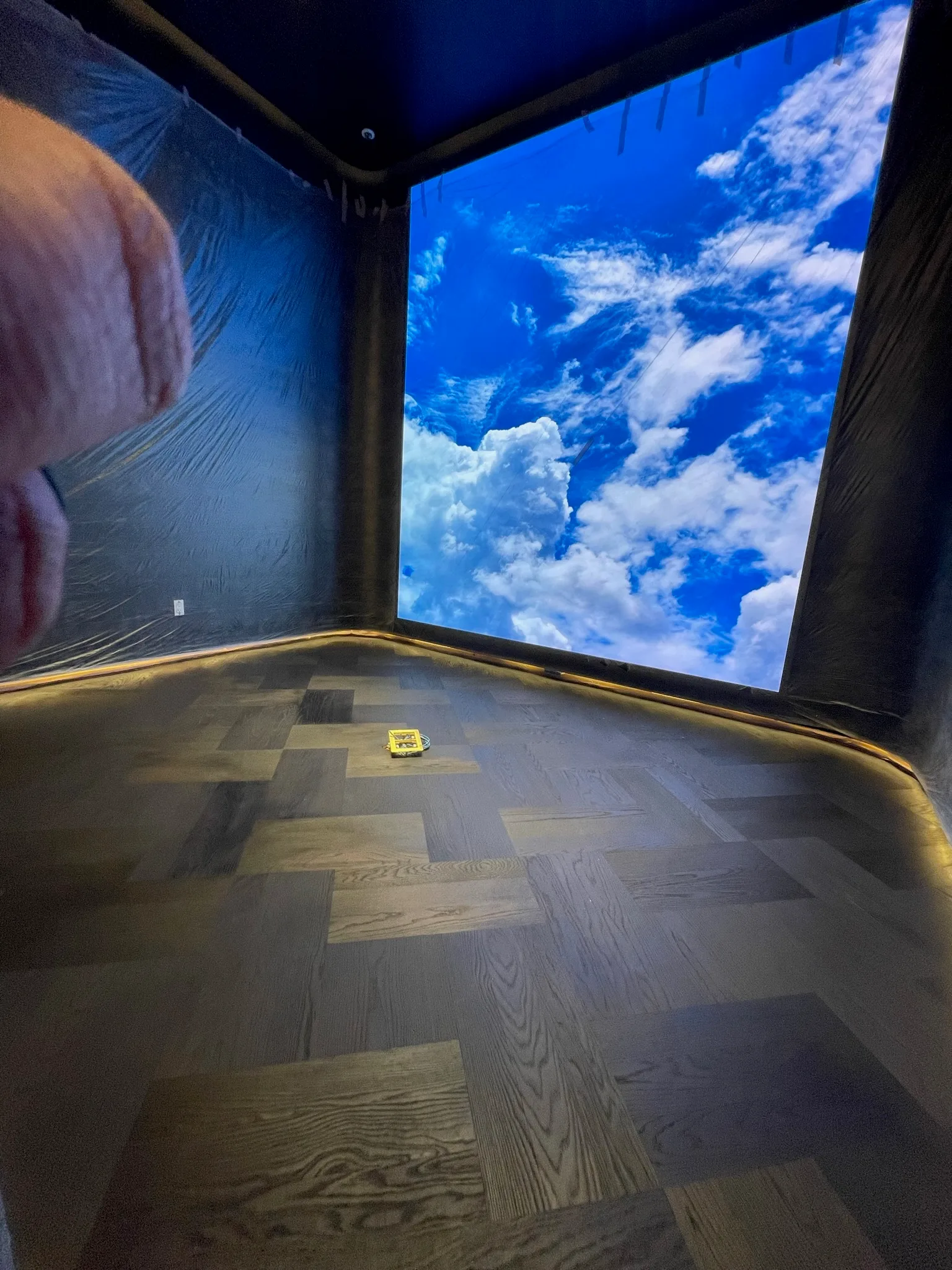 Custom basket-weave floor stained black on site with a commercial finish, beneath a sky video wall at Tiffany & Co. Glendale
