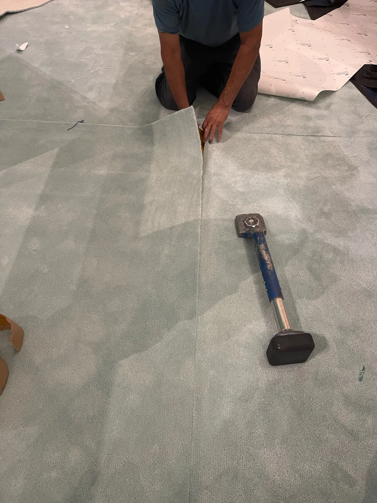 Cal Coast Flooring installer seaming the custom Tiffany-blue carpet, carpet hammer alongside