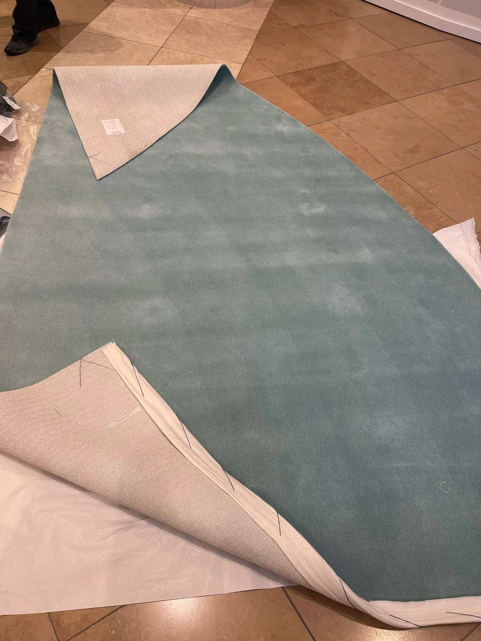 Custom Tiffany-blue carpet unrolled on the marble atrium floor before installation
