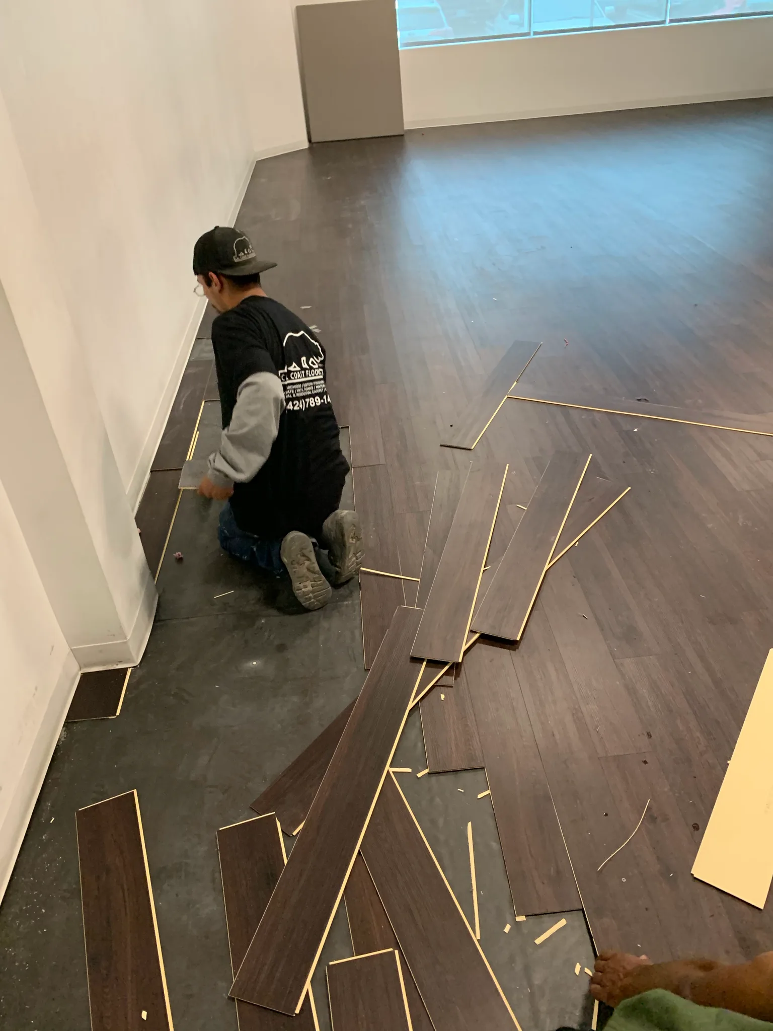 Cal Coast Flooring installer laying dark wood-look plank flooring in a tenant suite at Wedgewood