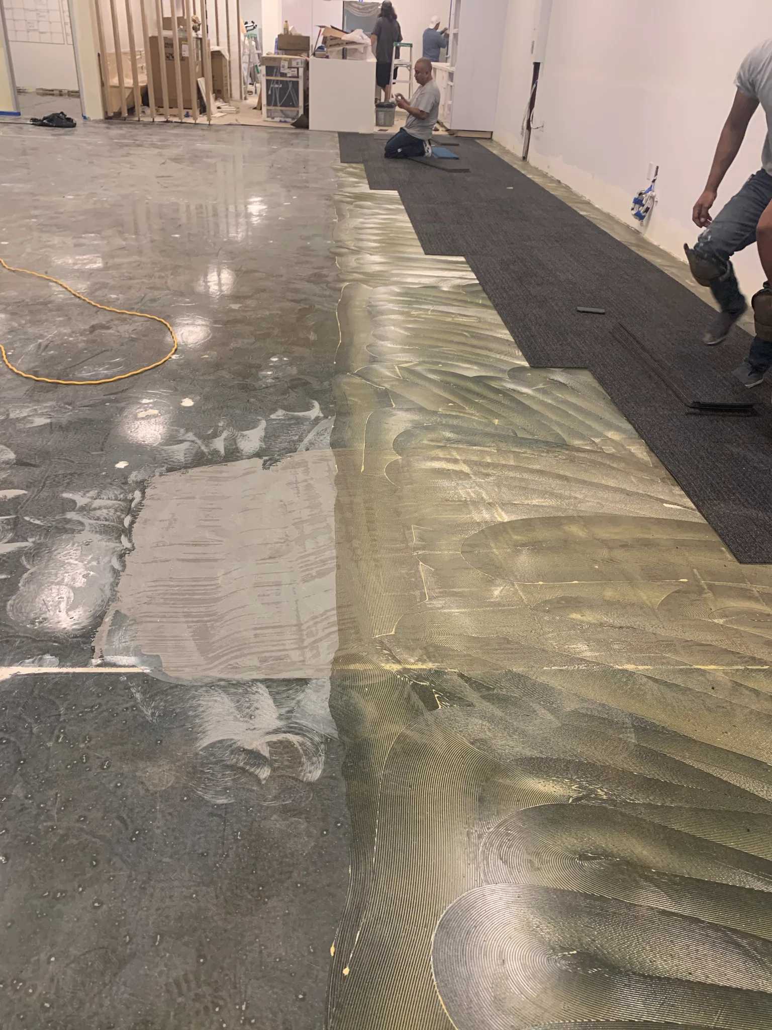 Carpet tile mid-install over the moisture barrier in a Wedgewood tenant space