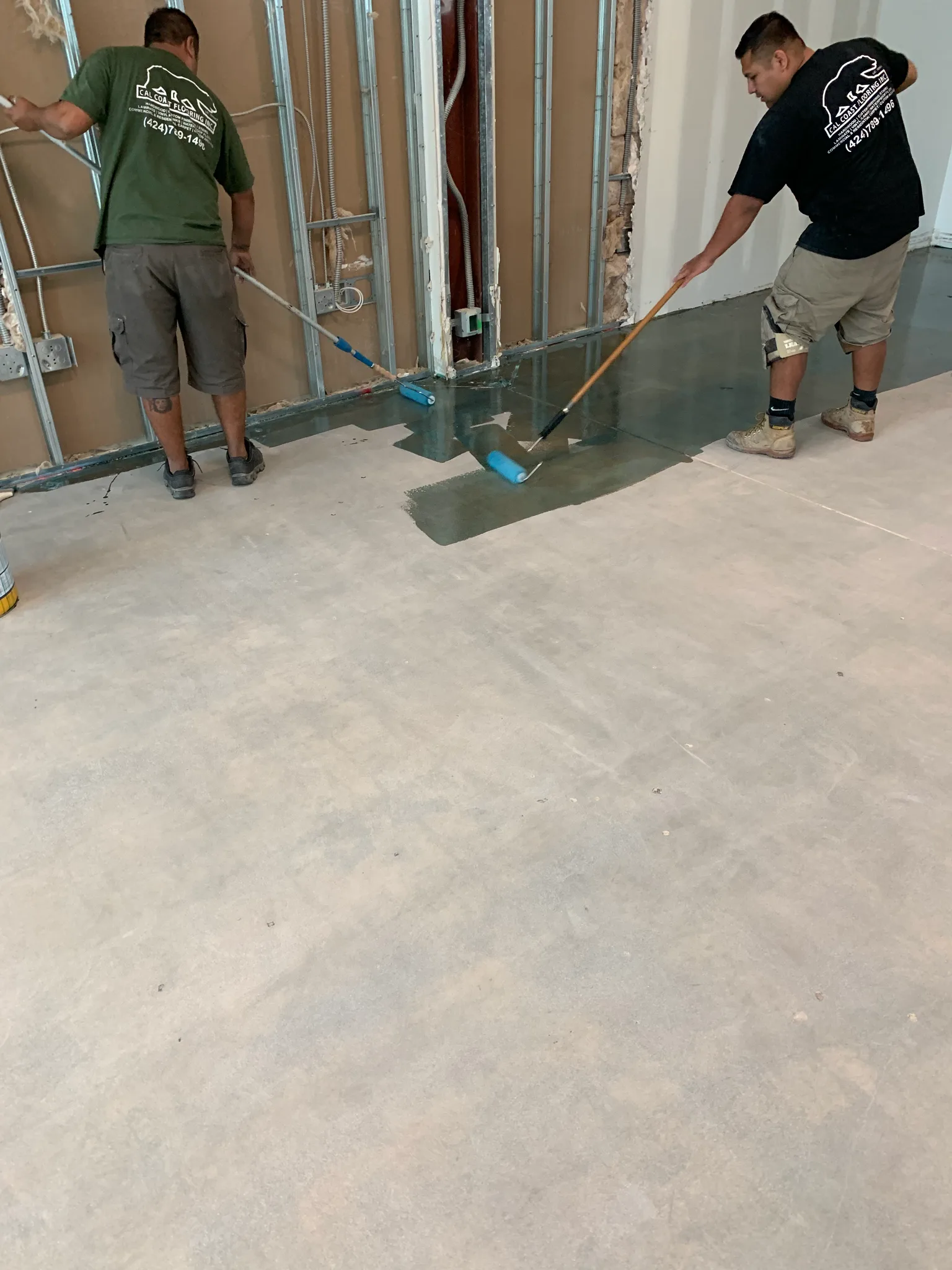 Cal Coast Flooring crew rolling a moisture barrier onto the bare concrete slab at the Wedgewood building