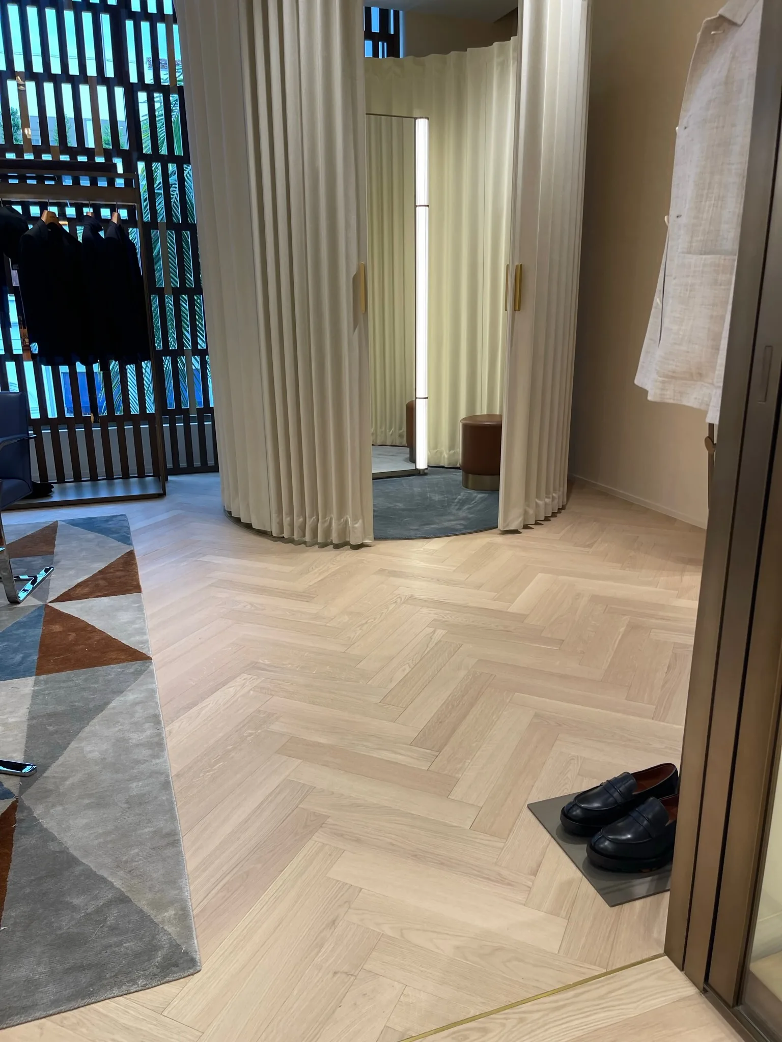 Oak herringbone floor detail beside the fitting-room curtains at Zegna Beverly Hills